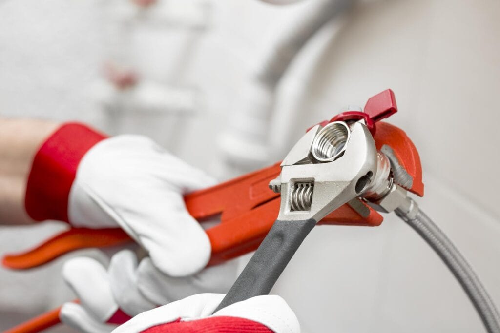 Plumber holding pipe wrenches for an emergency repair in Wellington