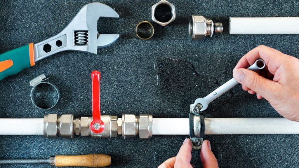 Plumber repairing a pipe valve with an adjustable wrench in Wellington