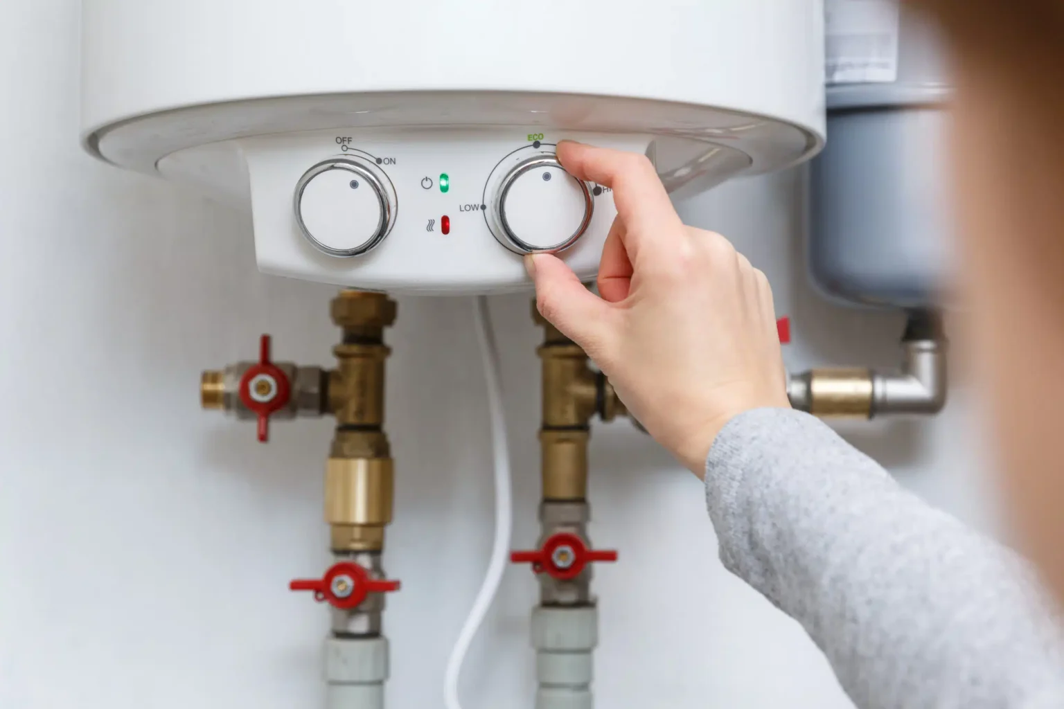 Homeowner adjusting the temperature controls on a water heater in Wellington